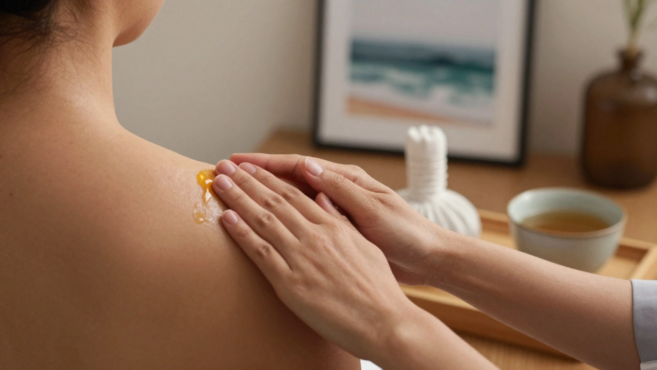 Therapist's hands applying gentle pressure with warm oil beside a herbal compress and tea, in a calm, clutter-free space.